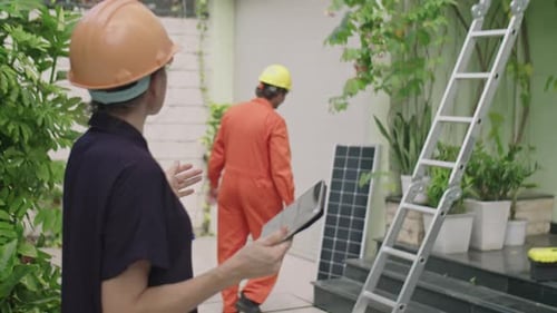 Ingenieurin kontrolliert Arbeiterin installiert Solarpanel auf dem Dach