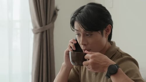 Young Man Talking on Phone While Drinking Coffee