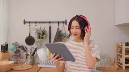 Young Woman Using Tablet in Kitchen with Headphones