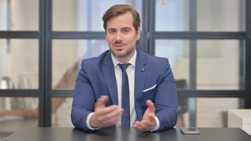 Talking Young Businessman Doing Video Chat in Office