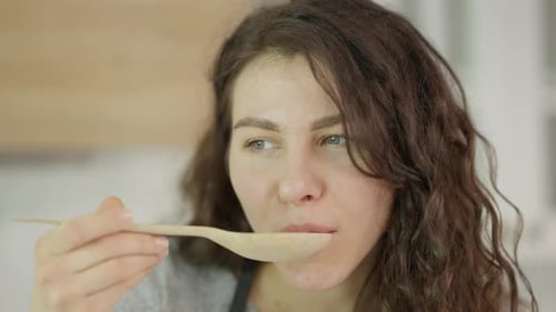 Woman Savoring Delicious Taste from Wooden Spoon