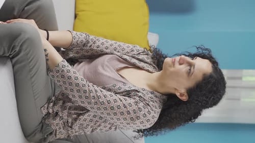 Worried Woman Sits on Couch Rubbing Hands