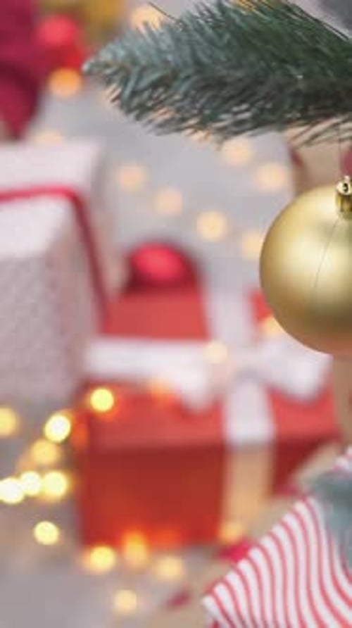 Child Arranging Christmas Gifts Near Decorated Christmas Tree