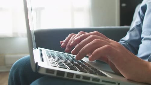 Closeup of a Man's Hands Typing Text on a Laptop Computer Keyboard