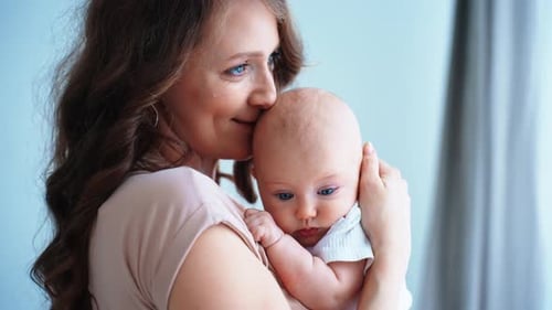 Loving Mother Cradling Adorable Baby in Sunlight