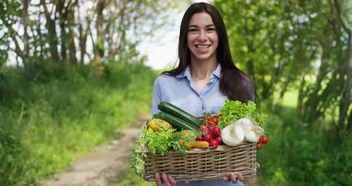 Beautiful young girl holding a basket of vegetables, in the background of nature. Concept: biology