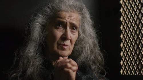 Faithful Senior Woman Praying inside Confessional Booth in Church