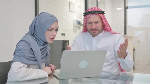 Man and Woman Looking at Laptop in Office