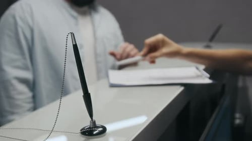 Unrecognisable Man Receiving Medical Form from Administrator and Signing It