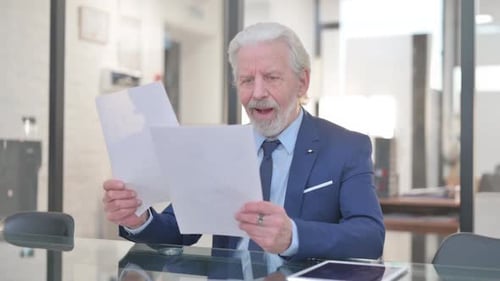 Senior Man Reacts Positively to Documents in Office
