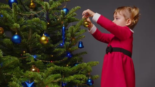 Child Decorating Christmas Tree with Festive Ornaments