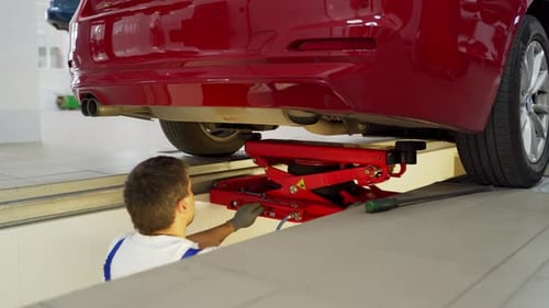 Auto Mechanic Inspects Vehicle Steering Suspension on Hydraulic Lift Car Service Tech Tests Analyzes
