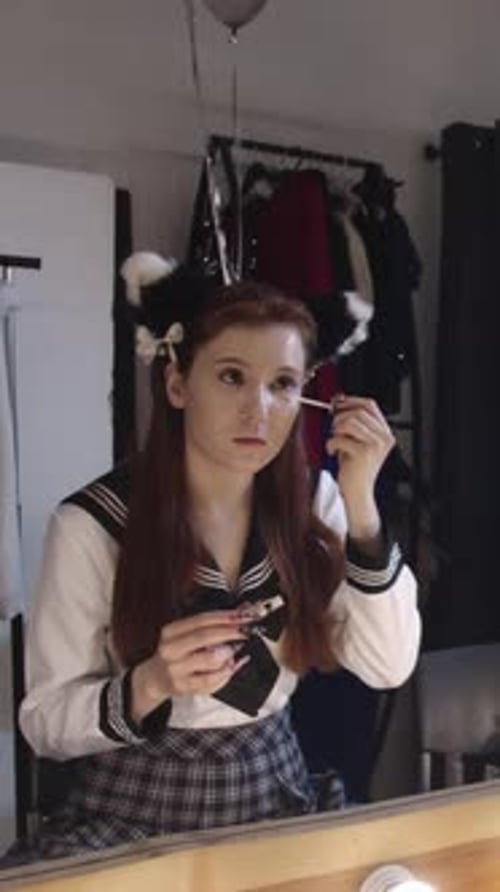 Süße junge Cosplayerin schminkt sich und trägt Concealer auf sie auf