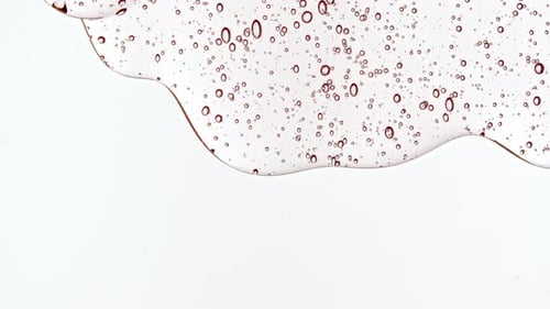 Gel cosmétique fluide transparent avec des bulles de molécules s'écoulant sur la surface blanche