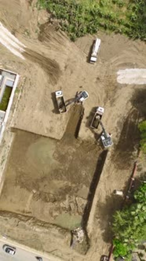 Excavator Filling Dump Trucks at Construction Site