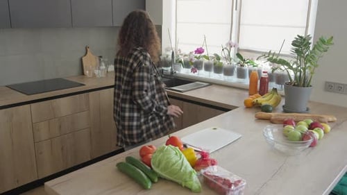 Woman Washing Food in a Bright Kitchen