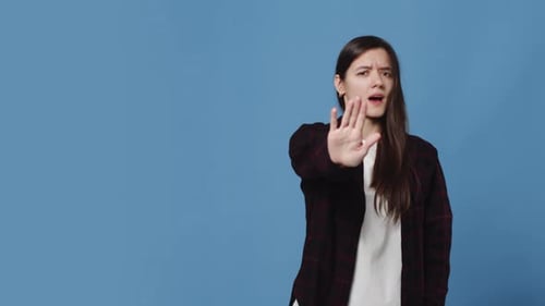 Young Woman Showing Stop Sign with Hand Gestures on Blue Background