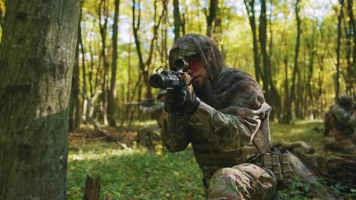 Man with Rifle Kneeling in Forest, Wearing Camouflage