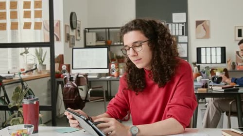Young Man Works on Tablet in Creative Workplace