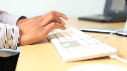 Male typing on keyboard on desk in office