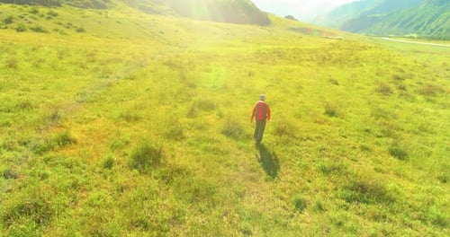 Flight Over Backpack Hiking Tourist Walking Across Green Mountain Field Huge Rural Valley at Summer