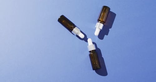 Close up of dropper serum bottles on blue background with copy space