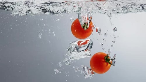 Tomatoes falling into boiling clean water. Light background, close up, slow motion
