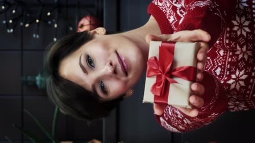 Woman Offering Christmas Gift with Red Ribbon