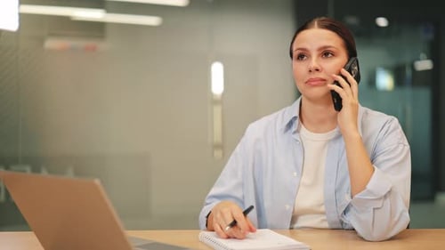 Professional Woman Engaged in Serious Phone Call at Office Desk