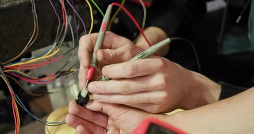 Mecánico que usa un multímetro en el cableado de un automóvil en un taller de reparación de automóviles