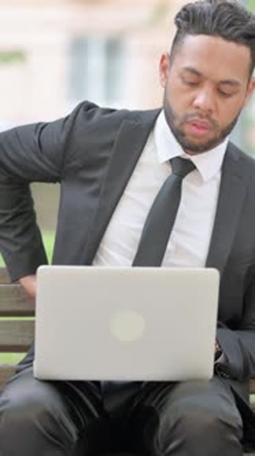 Vertical video, Businessman with Back Pain Using Laptop Outdoor