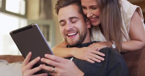 Affectionate Couple Using Tablet at Home Together