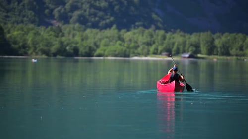 Kayaking on a serene lake surrounded by lush greenery in the afternoon sun