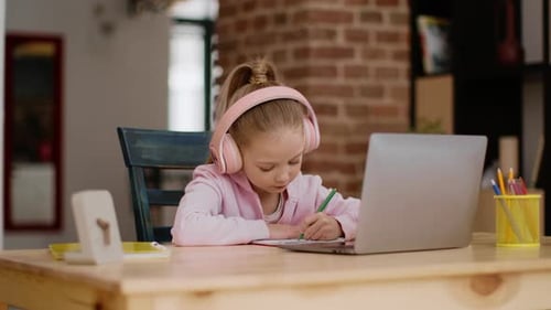Focused Girl Doing Homework with Laptop and Headphones