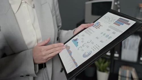 Close up of Unrecognizable Woman Reading Graphs and Charts Off Paper in Office