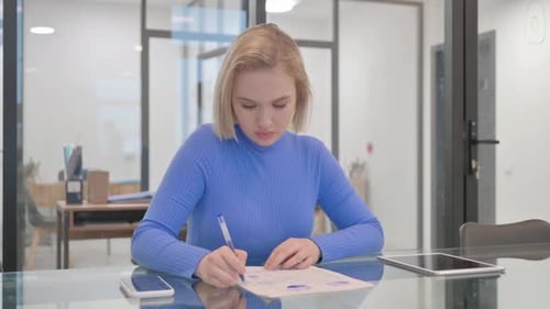 Young Adult Working at Glass Desk in Office