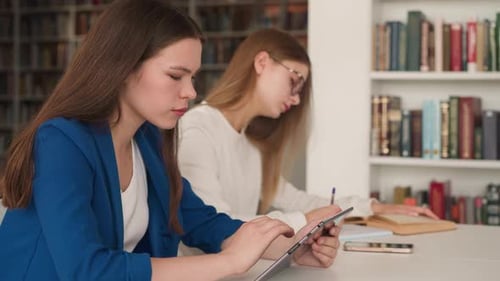 Woman Surfs Internet on Tablet in Library Hall