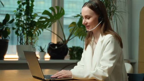 Woman a Call Center and a Computer with a Headset Advising on Telemarketing Customer Service or