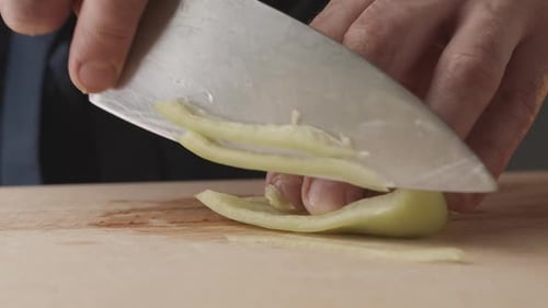 Front View of the Young Chef Cut Thin Slices of a Piece of Green Pepper