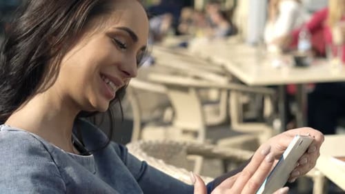 Attractive young woman relaxes with tablet at outdoor cafe in bustling city
