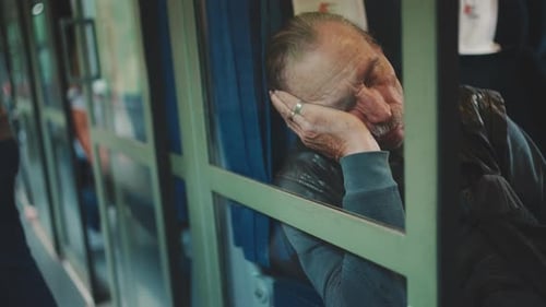 Vieil homme dormant alors qu'il voyage dans un coupé, vue à travers la vitre d'un coupé