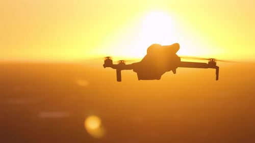 Drohne fliegt bei Sonnenuntergang Ferngesteuerter Quadcopter wird für Luftaufnahmen über der ländlichen Skyline in der Abenddämmerung verwendet
