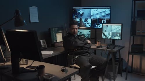 Security Guard Monitoring Surveillance Screens in Control Room