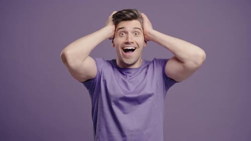 Excited man with hands on head smiles widely