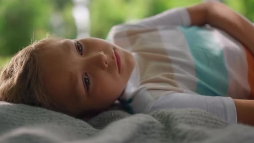 Portrait of Tranquil Cute Boy Lying on Blanket Closeup. Blondhair Happy Kid
