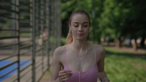 Young Female Jogger Start to Run Holding the Phone and Turns on the Music to Listen in Her Earphones
