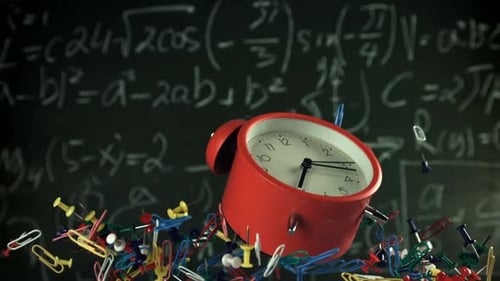Alarm Clock and School Tools Soaring Up Against the Blackboard Background Filmed on a Highspeed