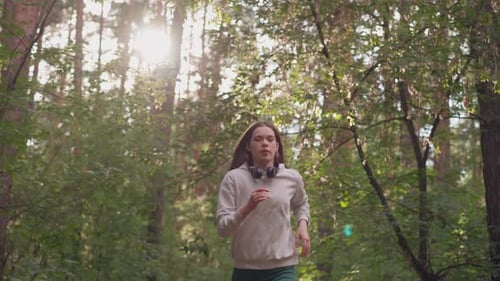 Young Woman Athlete Jogging in Forest