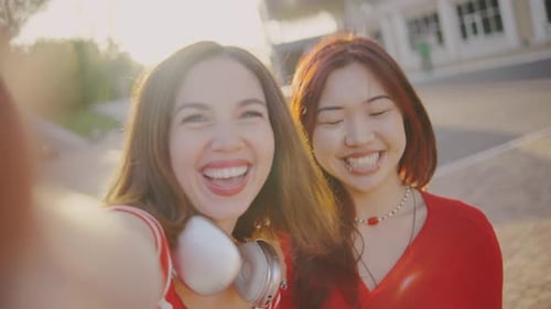 Two Girls Take a Selfie While Walking in the Park Girls in a Good Mood Take a Selfie on a Smartphone