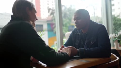 Happy diverse couple holding hands together at coffee shop. Two lovers dating at cafe place
